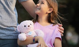 Jente holder rosa bamse med sporing
