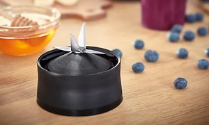 Bosch VitaPower blenderens motor med knivblad på bordet ved siden av blåbær og honning