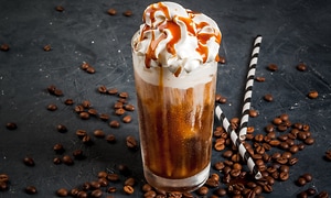 A tall glass with Frappuccino coffee drink topped with whipped cream