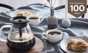 Blooming coffee maker on a table next to coffee cups and pastries and text try at home 100 days