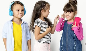 Gutt med on-ear hodetelefoner og to jenter med telefon og in ear hodetelefoner