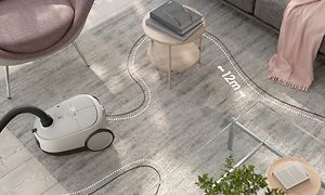 Hvit Electrolux Clean 600 Støvsuger med pose i stuen og illustrasjon som viser dens 12 meter radius