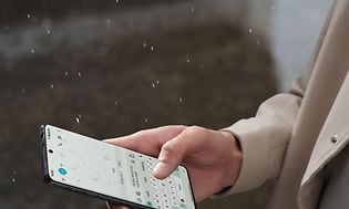 Telecom - OnePlus - OnePlus 12 - Person tekster på en OnePlus 12 i regn