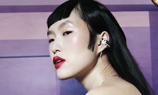CE - Bose Ultra Open Earbuds - Dame har på Bose Earbuds med en lilla bakgrunn