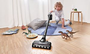 Et barn rengjør gulvet ved leker rundt seg med en Bosch-støvsuger