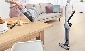 Dame bruker Bosch Serie 4 Flexxos håndholdte støvsuger for å rengjøre smuler på stuebordet