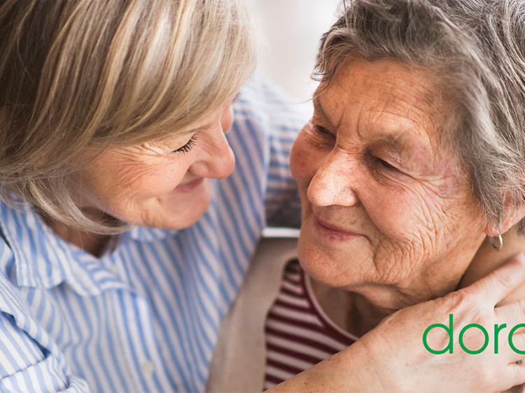 To eldre damer som smiler til hverandre og grønn Doro logo