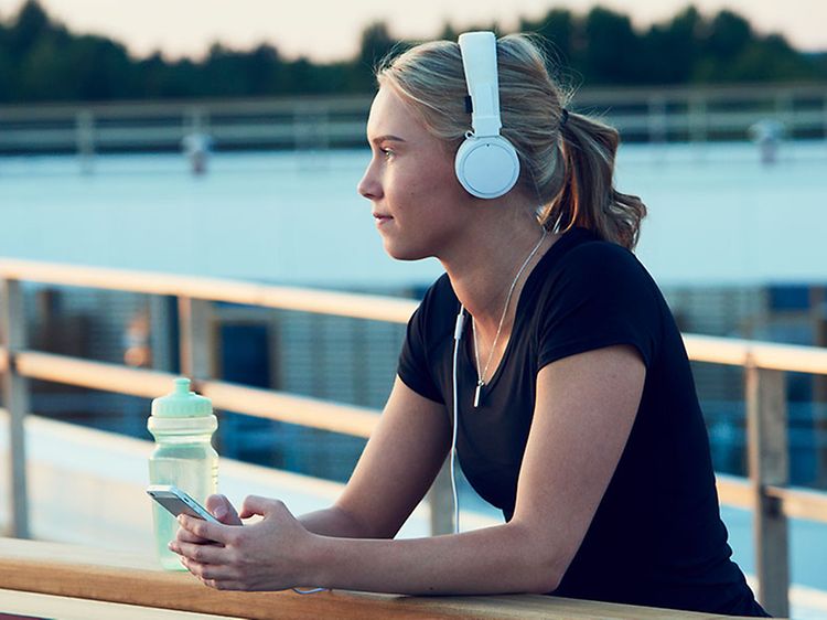 en kvinne på løpetur har på hodetelefoner og hører på podcast