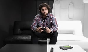 Mann holder en spillkontroll i et svart og hvitt rom med Nvidia Shield 