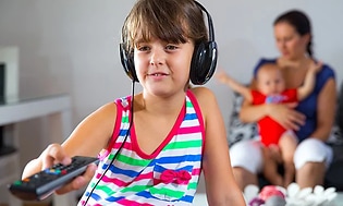 En unge har på seg trådløse hodetelefoner mens han trykker på fjernkontrollen