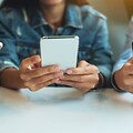 tre ungdommer bruker smarttelefon ved et bord