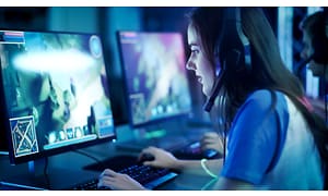 kvinne med gaming-headset spiller dataspill på skjerm