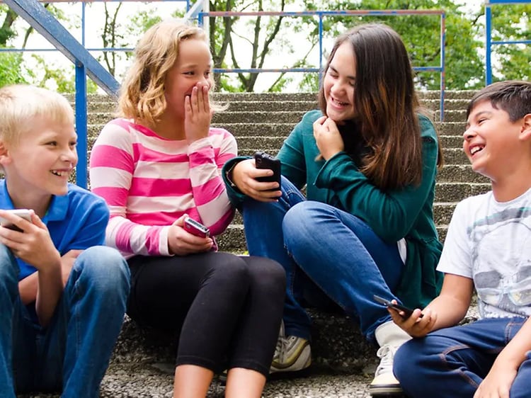barn i trapp ler med smarttelefoner i hendene
