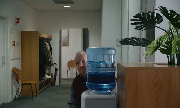 Mann som gjemmer seg bak en vann vannkjøler