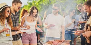 People gathered around a grill serving themselves and having a good time