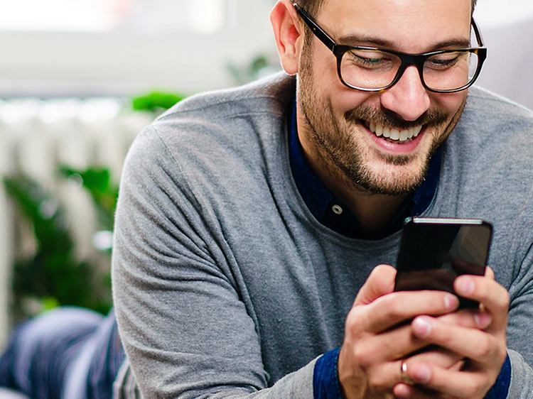 mann holder smartphone og smiler mens han ser på den