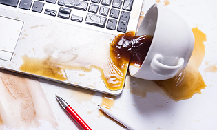 kaffekopp veltet og sølt utover en laptop