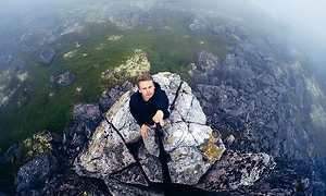 mann med selfie-stick på toppen av et tåkete fjell