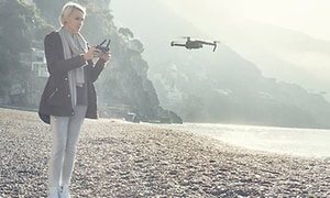 Kvinne på strand flyr drone