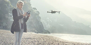 Kvinne på strand flyr drone
