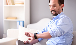 mann ser smilende på smartklokke på armen sin