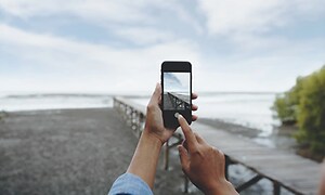 person tar bilde av strand med smarttelefon