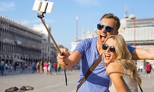 mann og kvinne poserer for selfie med smarttelefon og selfie stick