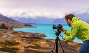 mann med kamera på stativ i vakkert naturlandskap