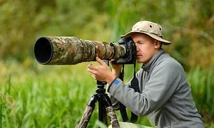 mann fotograferer med kamera med gigantisk zoomobjektiv på