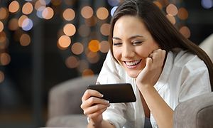 Kvinne holder smarttelefon og smiler