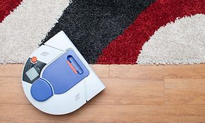 hvit robotstøvsuger på tregulv med et sort rødt og hvitt teppe