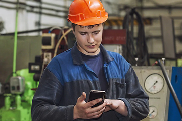 mann ser på robust smarttelefon i arbeidsuniform med hjelm på
