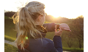 kvinne ser på gps på smartklokken sin i solnedgang