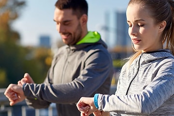 kvinne og mann sjekker sportsklokke, smartklokke eller aktivitetsmåler på joggetur