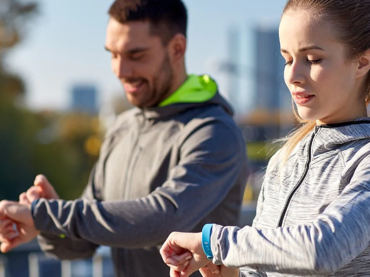 kvinne og mann sjekker sportsklokke, smartklokke eller aktivitetsmåler på joggetur