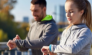 kvinne og mann sjekker sportsklokke, smartklokke eller aktivitetsmåler på joggetur