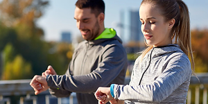 kvinne og mann sjekker sportsklokke, smartklokke eller aktivitetsmåler på joggetur