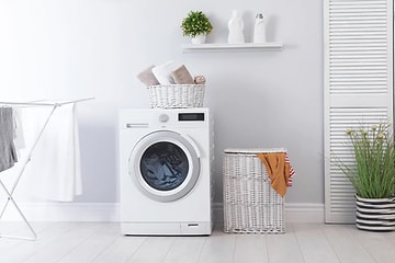 hvit, kombinert vaskemaskin og tørketrommel står på et hvitt vaskerom