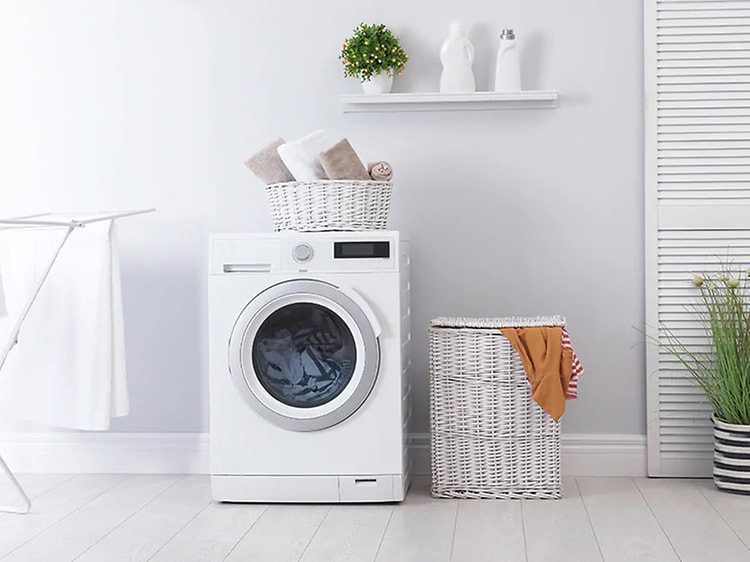 hvit, kombinert vaskemaskin og tørketrommel står på et hvitt vaskerom
