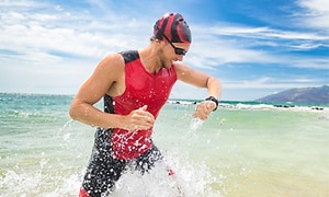 mannlig svømmer sjekker sportsklokke i havet