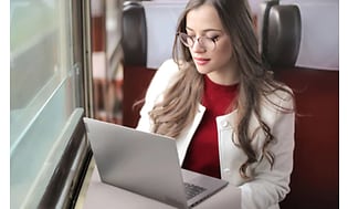 Kvinne leser på en Lenovo ThinkBook på et tog