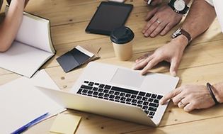tre personer samarbeider rundt en laptop