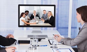 4 personer har videomøte i møterom med 5 personer på skjerm