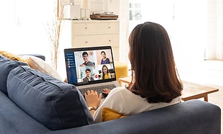 kvinne har et videomøte på laptop i sofa hjemme
