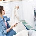 kvinne på gulv foran vaskemaskin med skittentøy