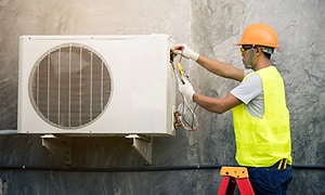 Elektriker monterer varmepumpe på vegg